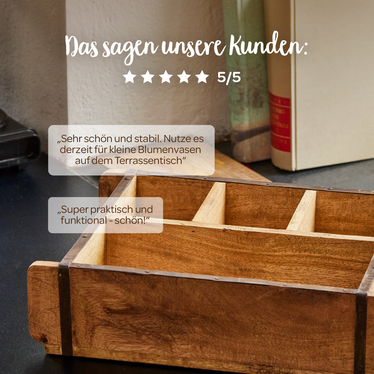 Sobre una mesa hay una caja de madera con compartimentos, al fondo hay libros; encima hay opiniones de clientes en alemán y cinco estrellas con una calificación de 5/5.