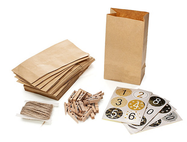 Kit de manualidades para hacer un calendario de Adviento con bolsas de papel marrón, pinzas de madera, hilo y pegatinas numeradas.