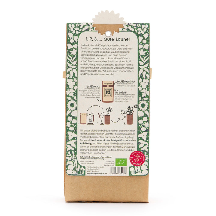 Parte posterior de un paquete con instrucciones en alemán para cultivar albahaca, borde verde decorativo y descripción de texto.