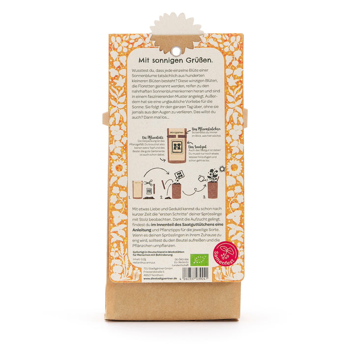 Reverso de un paquete con instrucciones en alemán para cultivar girasoles, ilustrado con imágenes paso a paso y un patrón de girasol amarillo.