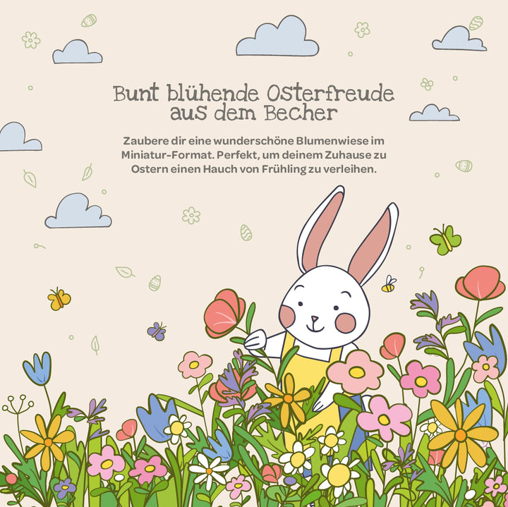 Ilustración de un conejo blanco en un prado colorido con flores primaverales, mariposas y nubes; en la parte superior hay un texto en alemán sobre la alegría de Pascua y la decoración floral.