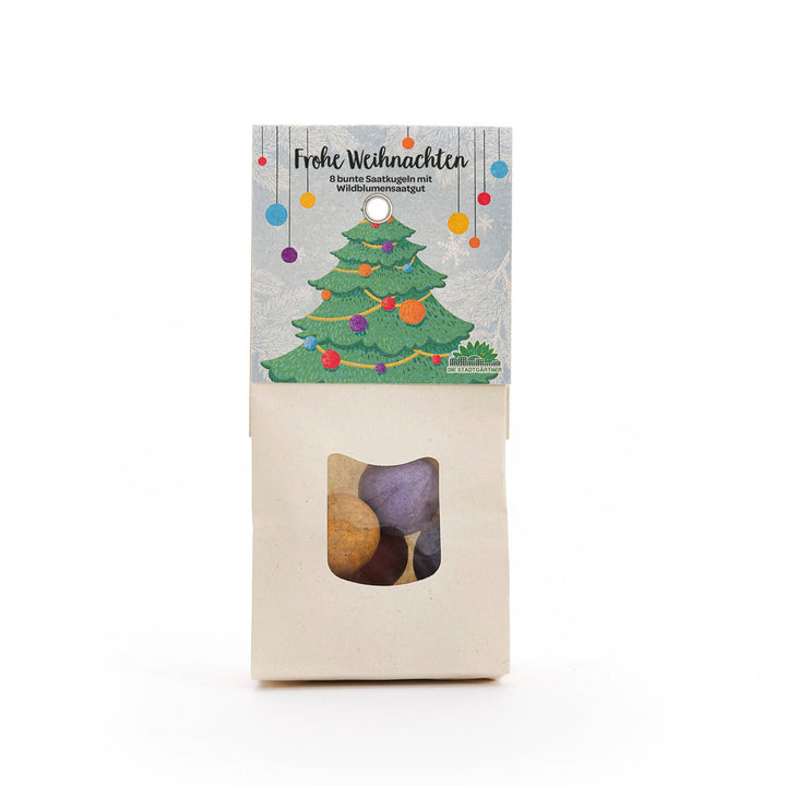 Bolsa de bolas de semillas de colores, envueltas de manera navideña con una etiqueta que representa un árbol de Navidad decorado y las palabras "Feliz Navidad".