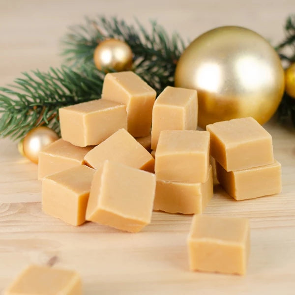 Pila de cubos de caramelo con ramas de abeto y bolas navideñas al fondo