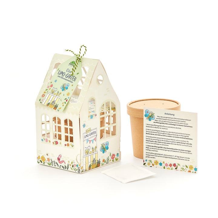 Un kit de manualidades para que los niños planten melisa, compuesto por una casa decorativa de cartón, una maceta, una bolsita de semillas e instrucciones.