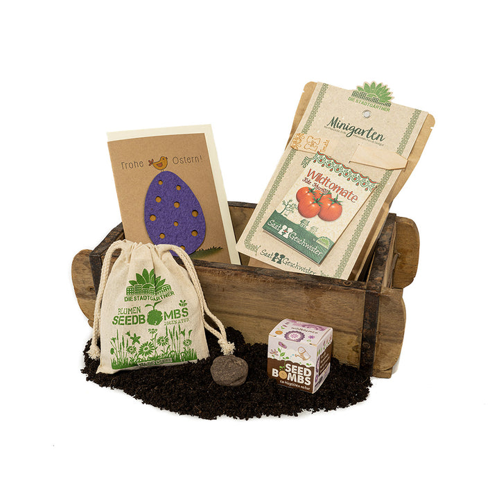 Kit de horticultura con bombas de semillas, kits de cultivo de plantas, tarjeta de Pascua y tierra presentado en una carretilla de madera.