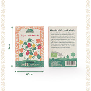 Dos paquetes de semillas de capuchina con ilustraciones de flores coloridas, una descripción y dimensiones de 9 x 6,5 cm sobre un fondo claro.