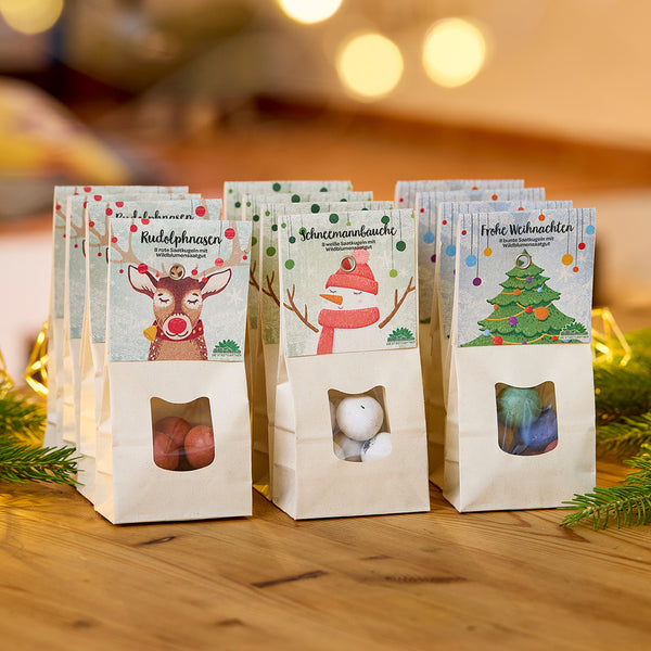 Tres bolsas de dulces decoradas con motivos navideños sobre una mesa de madera, cada una etiquetada con “Narices de Rodolfo”, “Barrigas de muñeco de nieve” y “Feliz Navidad”.