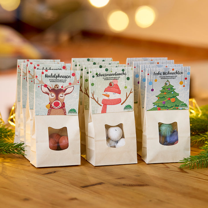 Tres bolsas de dulces decoradas con motivos navideños sobre una mesa de madera, cada una etiquetada con “Narices de Rodolfo”, “Barrigas de muñeco de nieve” y “Feliz Navidad”.