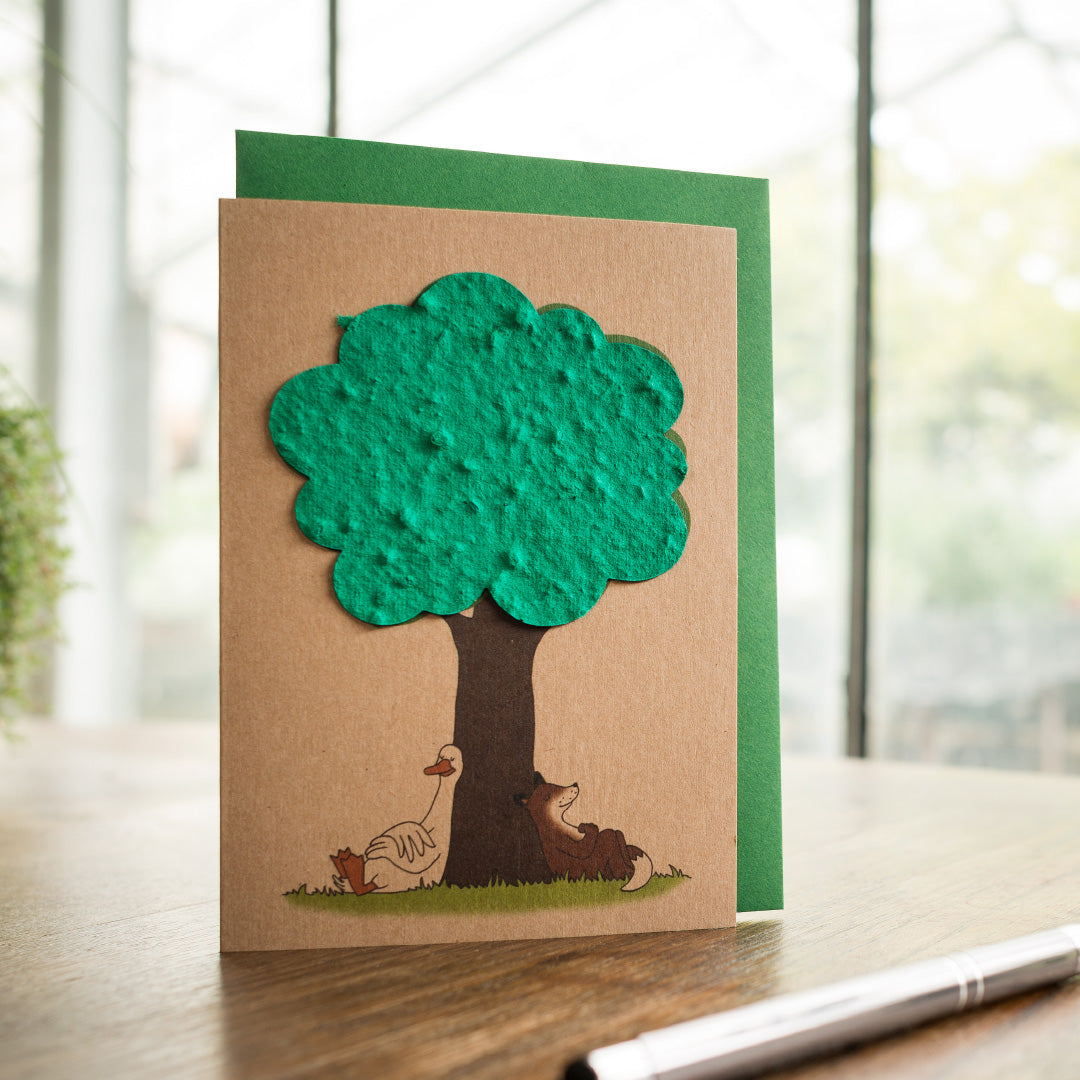 Tarjeta de felicitación hecha a mano con un árbol de papel verde y gallinas y un perro debajo.