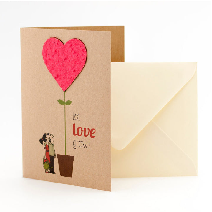 Tarjeta de felicitación con motivo de corazón y el texto "¡Deja que el amor crezca!", al lado un sobre.
