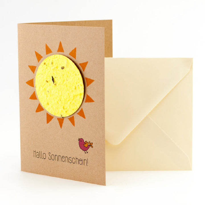 Tarjeta de felicitación con motivo de sol y la inscripción "¡Hola sol!" junto a un sobre de color crema.