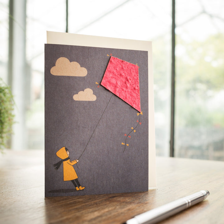 Tarjeta de felicitación con ilustración de un niño volando una cometa.