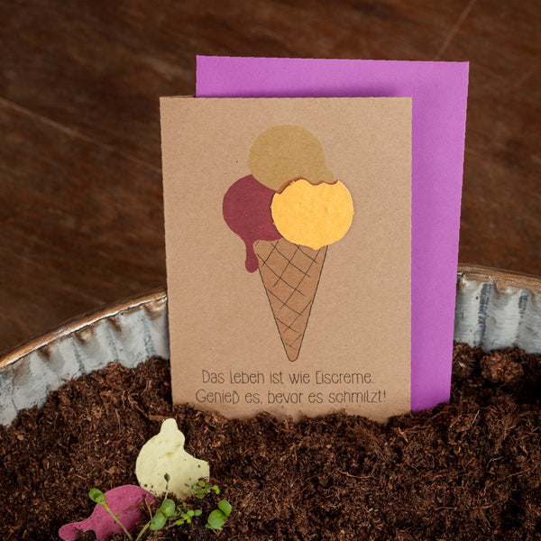 Tarjeta de felicitación hecha a mano con motivo de helado y la frase "La vida es como el helado. ¡Disfrútalo antes de que se derrita!" en el suelo.
