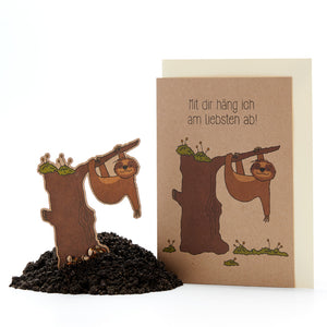 Divertida tarjeta de felicitación con figuras de perezosos colgando del tronco de un árbol, texto: "¡Me encanta pasar el rato contigo!"