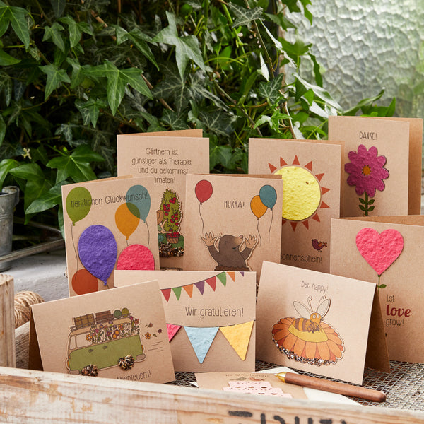 Varias tarjetas de felicitación hechas a mano con motivos coloridos y felicitaciones sobre una mesa de madera.