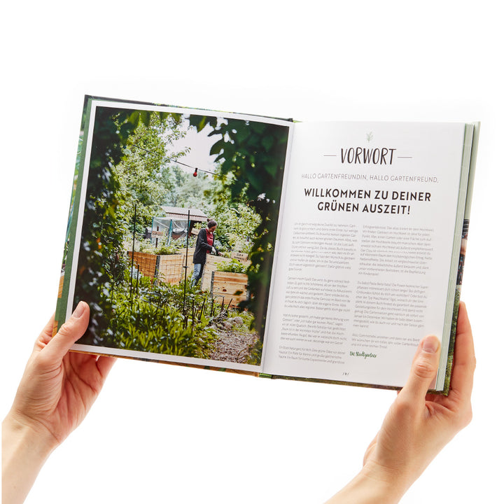 Persona sosteniendo un libro abierto con el título "Prólogo" y una imagen de un jardín.