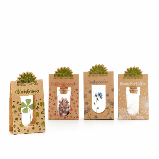 Cuatro pequeñas bolsas de regalo etiquetadas como "Amuleto de la suerte", "Persona favorita", "Consolador" y "Concededor de deseos", cada una con diferentes motivos vegetales.
