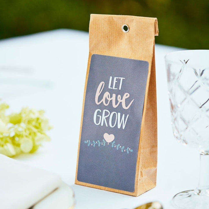 Bolsa de papel marrón con las palabras "Deja que el amor crezca" y decoración de corazón sobre una mesa preparada para la fiesta.