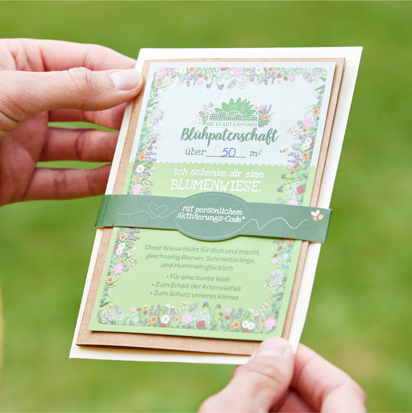 Manos sosteniendo una tarjeta de regalo para un pétalo de flor de más de 50 metros cuadrados con un diseño floral y texto.