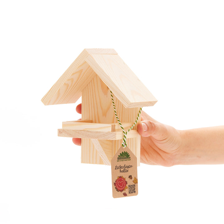 Casa de pájaros de madera sostenida por una mano con etiqueta de precio.