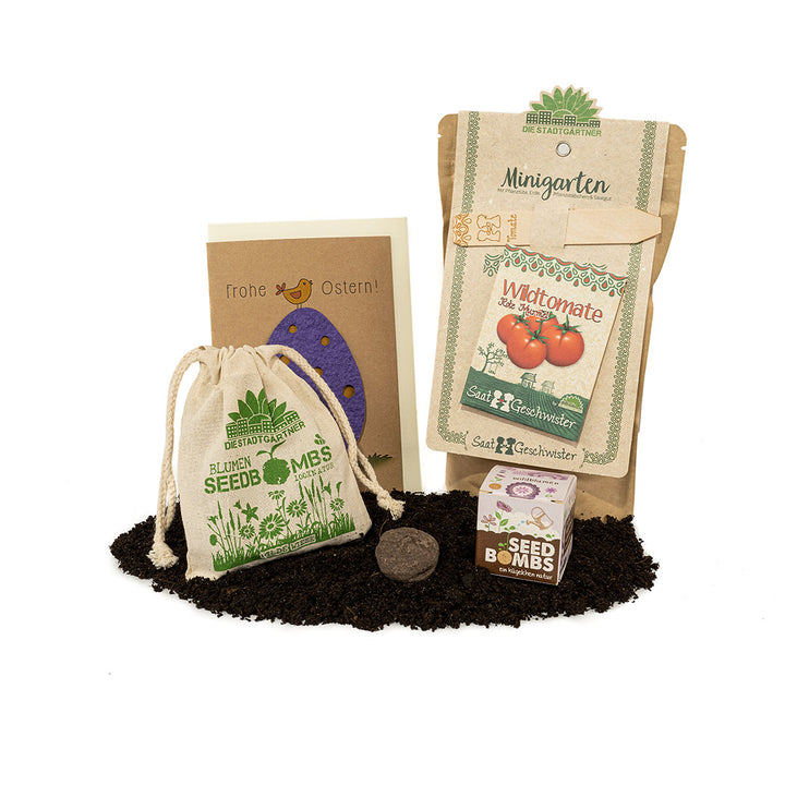 Juego de jardín con bolsas de semillas, bombas de semillas, tarjeta de Pascua y bolsa de yute sobre tierra.